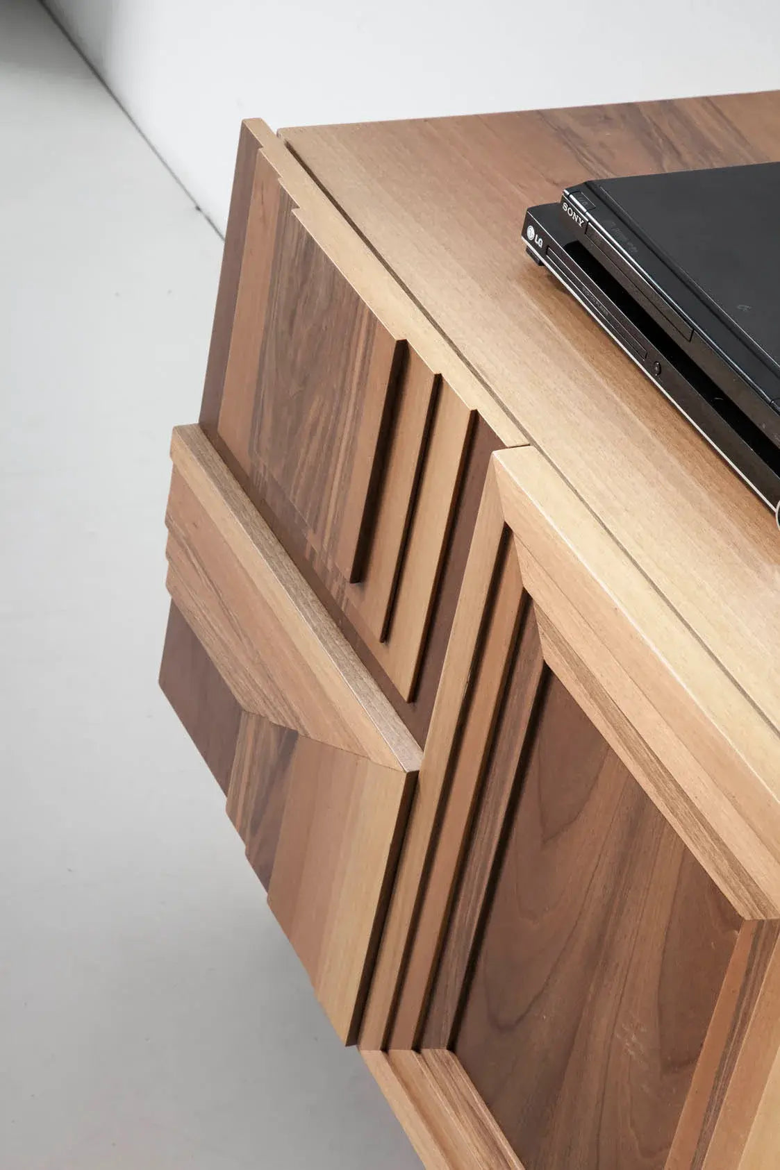 Detalle del mueble TV Totem Suspendido con relieves geométricos tallados y acabados artesanales en madera.