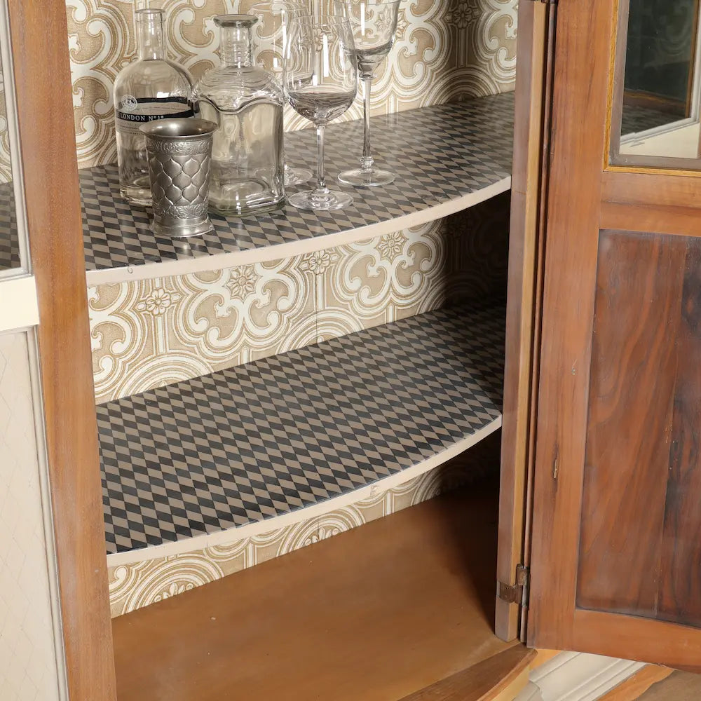 Detalle de los estantes de la Vitrina Arcadia con motivos geométricos y fondo ornamental en tonos neutros.
