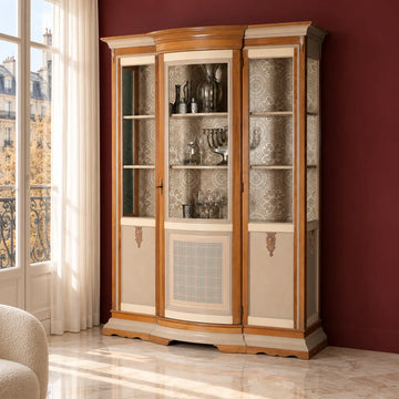 Vitrina Arcadia en un salón elegante con pared burdeos, mostrando copas y objetos decorativos en su interior.