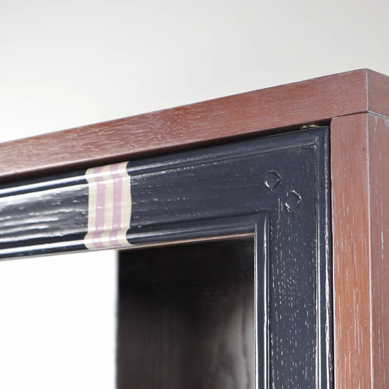 Detalle del marco superior de la Vitrina Astra con acabado amaderado y franjas decorativas en tonos suaves.