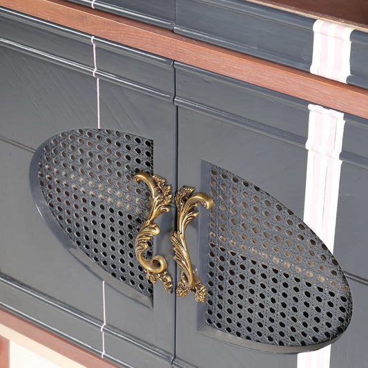 Detalle de las puertas inferiores con rejilla oscura, líneas pintadas y tiradores ornamentales dorados.