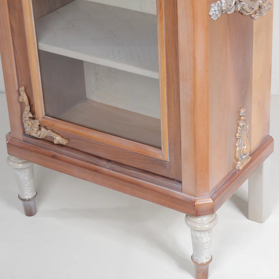 Detalle de puerta acristalada, patas decorativas y acabado en tonos madera de la vitrina Merlín.