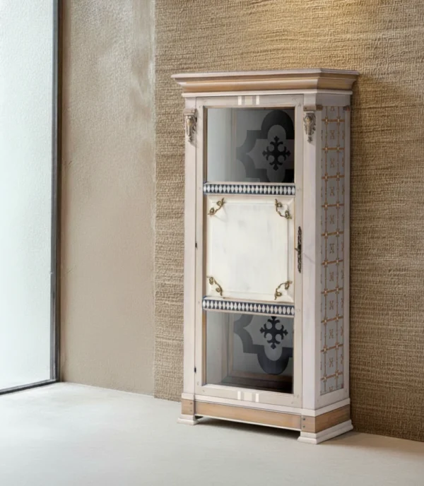 Vitrina San Juan alta: Mueble de diseño con puerta dividida en paneles de cristal y blanco, patrones geométricos laterales y herrajes dorados