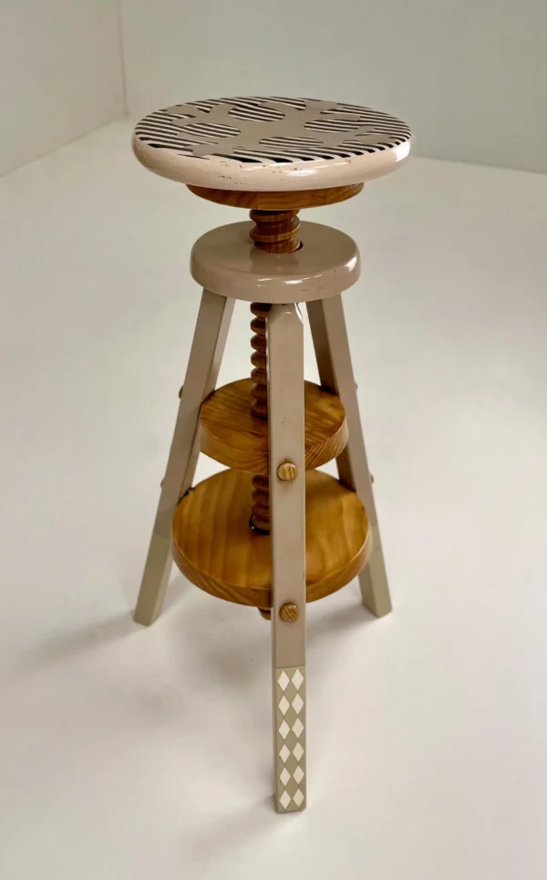 Taburete Boucle ajustable con estructura de tres patas y acabados en madera lacada