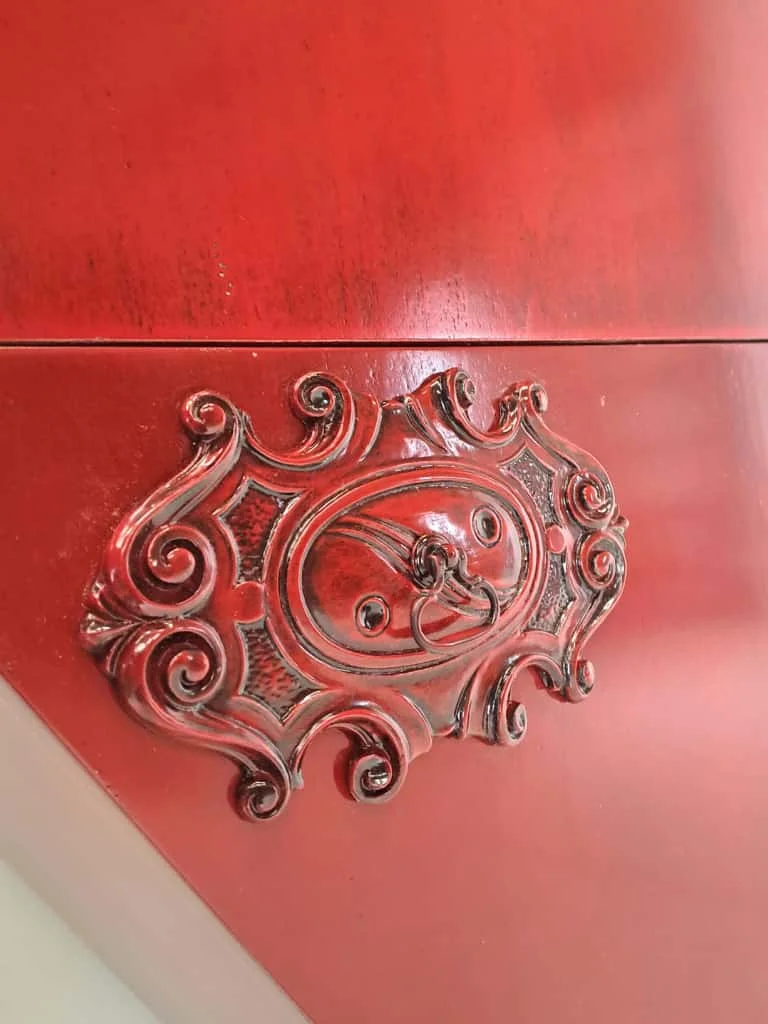 Herraje y detalle tallado del Mueble Corazón en acabado rojo.