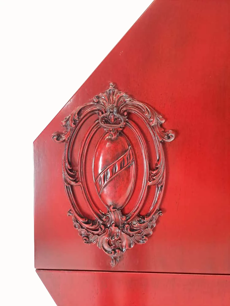 Detalle tallado del Mueble Corazón mostrando el relieve ornamental en rojo.