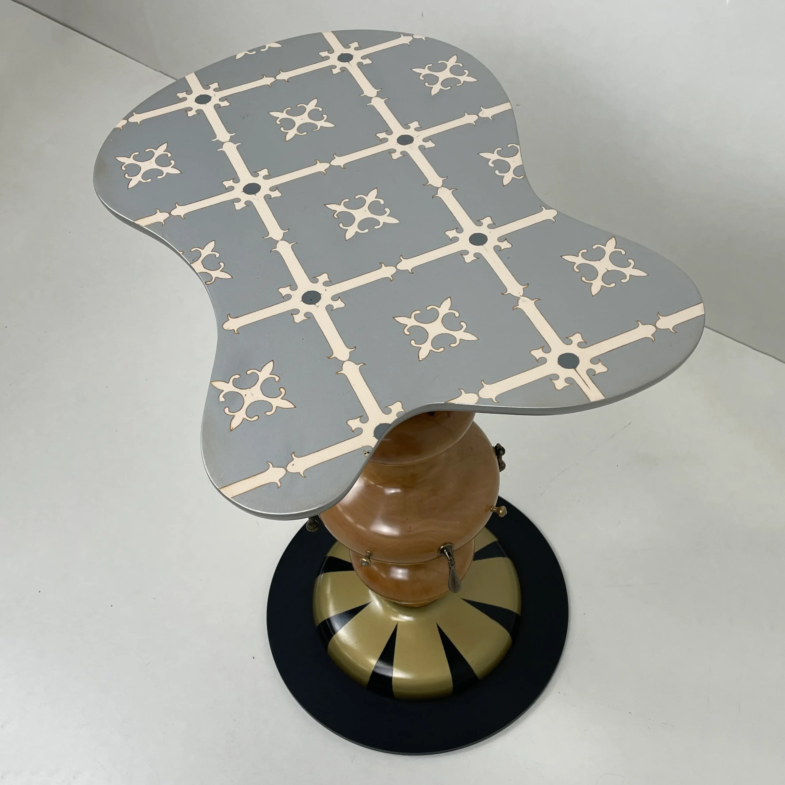 Mesita de noche original con pie central de madera torneada y base decorada a rayas.