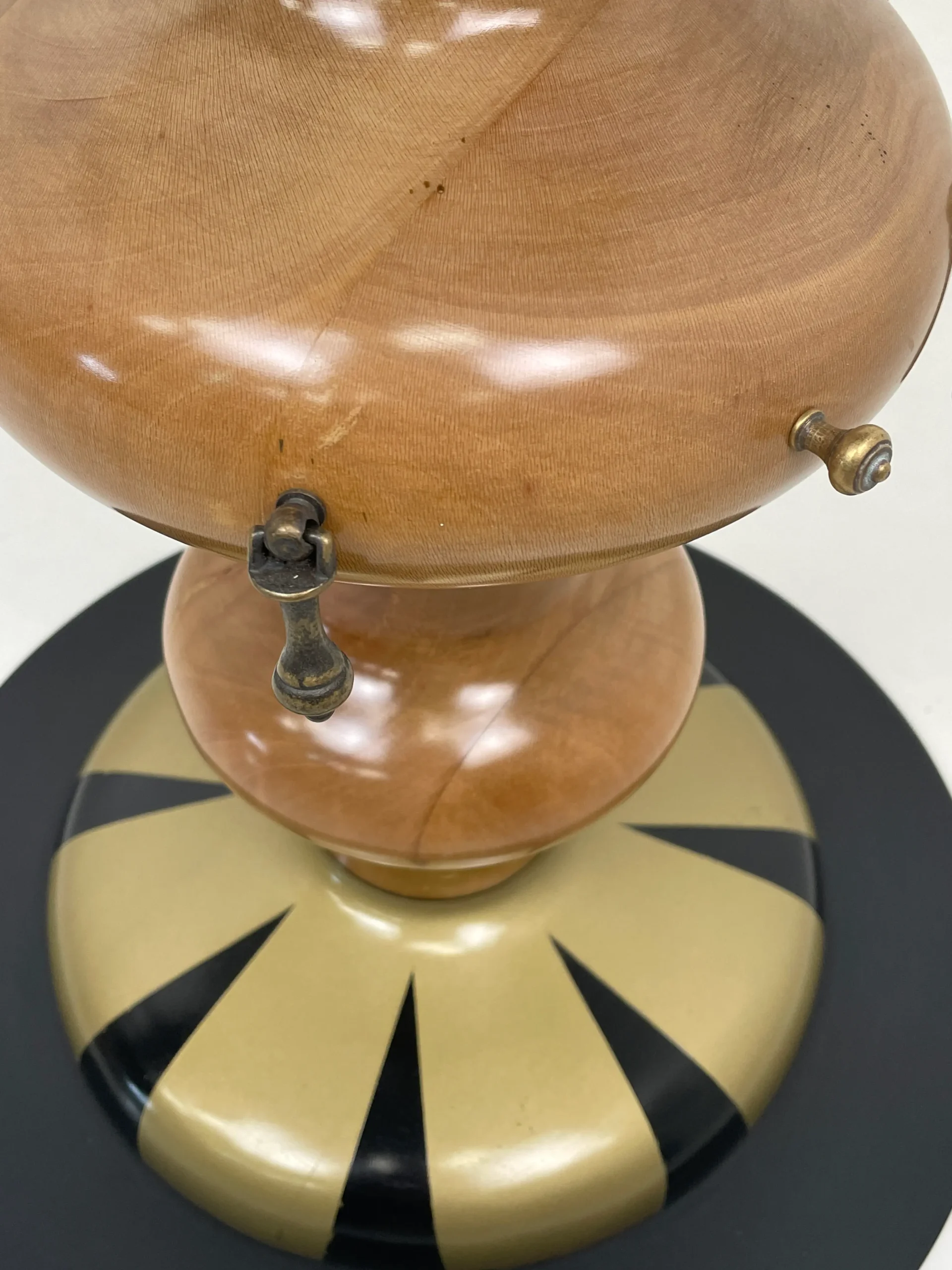 Detalle de la columna central de madera brillante con pequeños ganchos decorativos de latón.