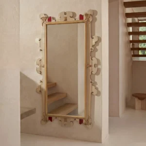 Primer plano que muestra los detalles ornamentados y apliques dorados en las esquinas del marco del espejo.